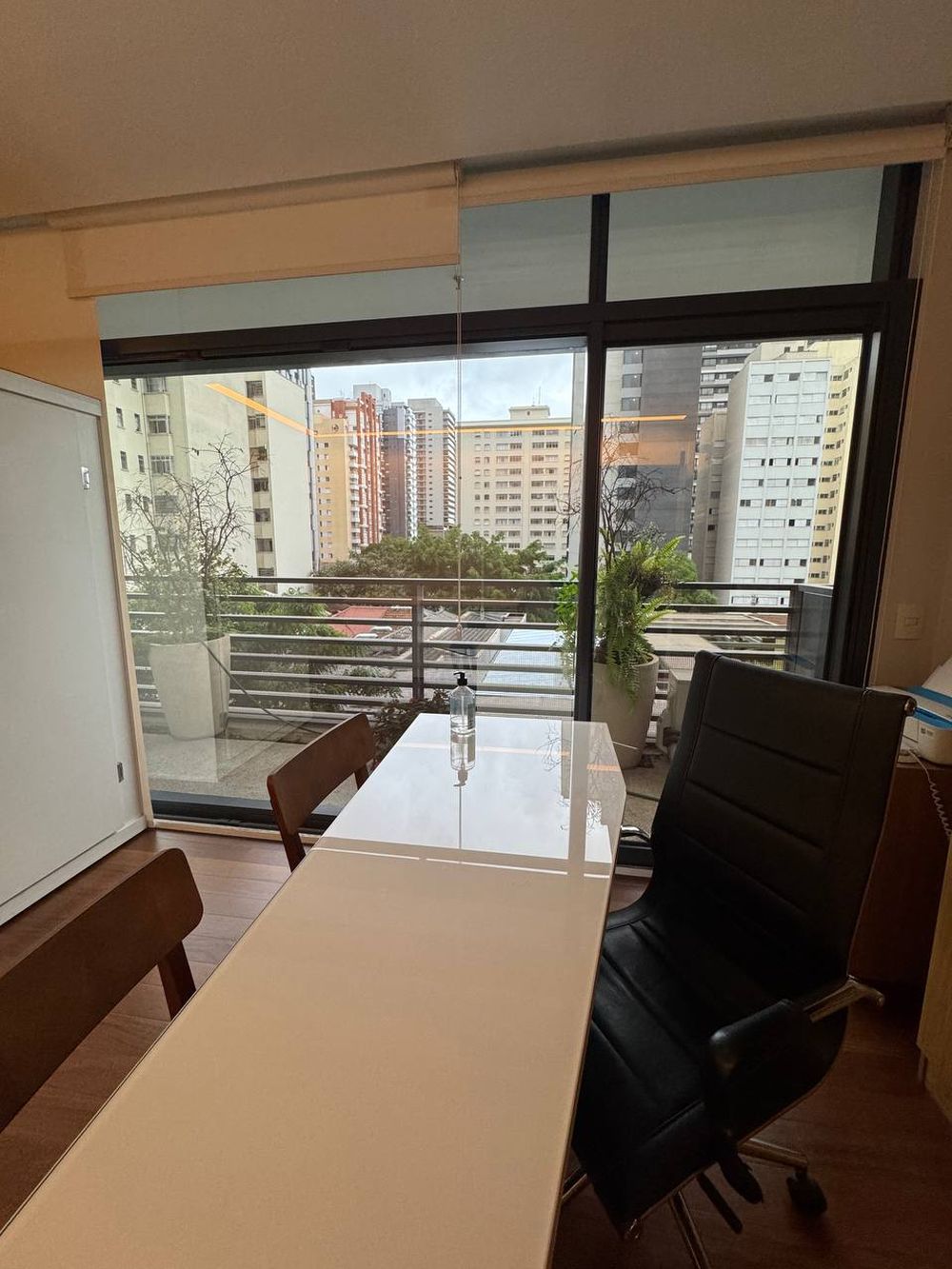 Sala de atendimento com mesa e vista para os prédios de Pinheiros